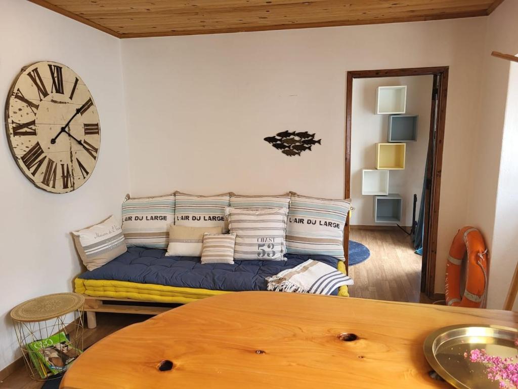 a living room with a couch and a clock on the wall at Charming Studio apartment in Sintra, Penedo in Colares