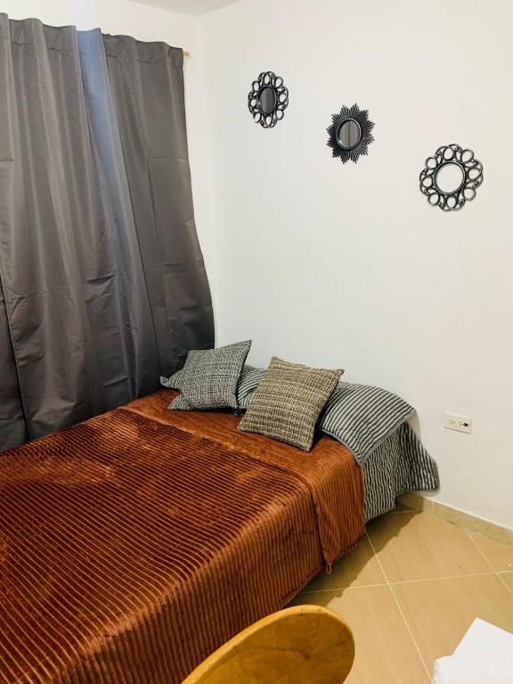 a bedroom with a bed with two clocks on the wall at Habitación en Sabaneta in Sabaneta