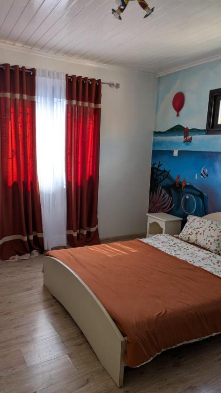 a bedroom with a large bed with red curtains at Résidence Hay Guest House in Antananarivo