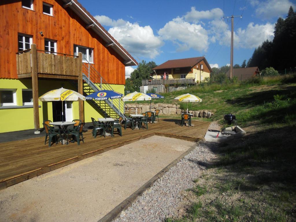 a deck with tables and umbrellas next to a building at Gîtes du Saut des Cuves in Xonrupt-Longemer