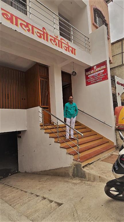 a man standing on the stairs of a building at Balaji Lodging in Pandharpur