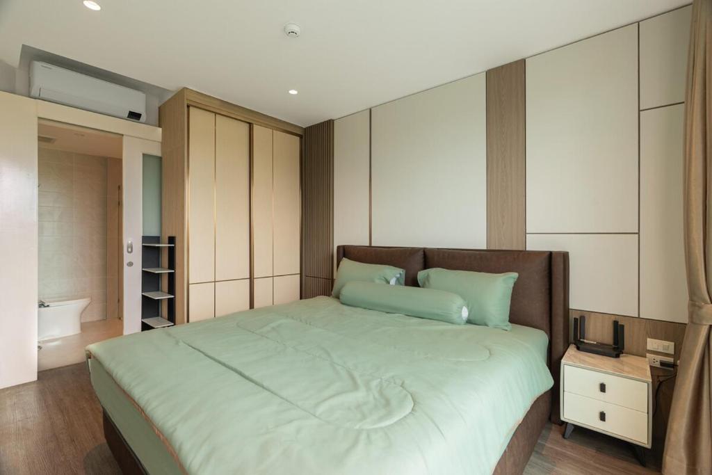 a bedroom with a large bed with green pillows at Modern 1BR Condo w Balcony Near Central Phuket in Ban Na Khua