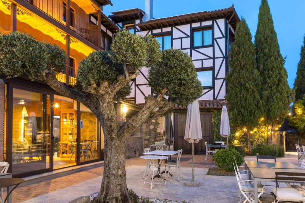 a tree in front of a building with tables and chairs at Aura del Jerte in Jerte
