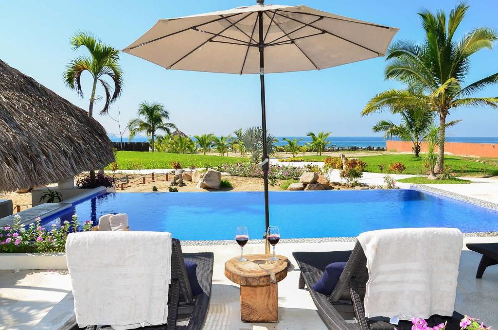 ein Tisch mit Sonnenschirm neben einem Swimmingpool in der Unterkunft El Secreto Residencial in Ixtapa-Zihuatanejo International