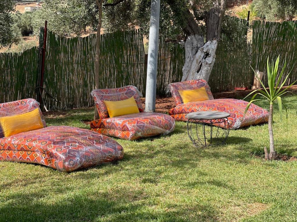 four cushioned chairs and a table in a yard at Ferme Erraha in Bhalil