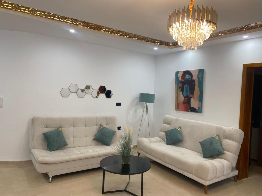 ein Wohnzimmer mit zwei weißen Sofas und einem Kronleuchter in der Unterkunft Charming 2-Bedroom Apartment with Garden View Balcony in Hammamet