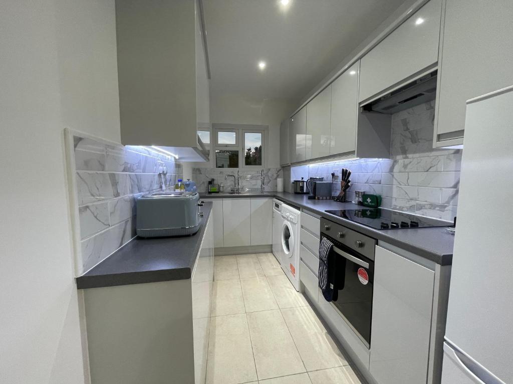 eine große Küche mit weißen Schränken und einem Waschbecken in der Unterkunft 4 Bedroom Terraced House with Huge Garden in Pinner