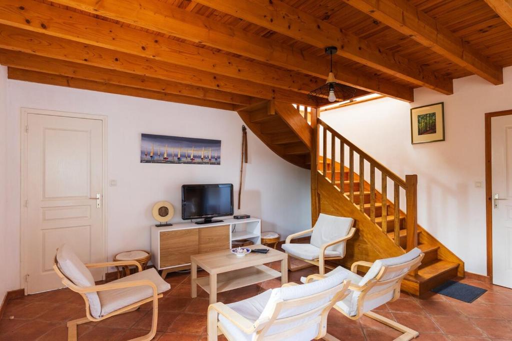 uma sala de estar com cadeiras brancas e uma escada em Charmante maison au cœur d'Hengoat em Hengoat