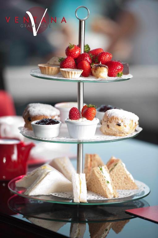 a three tiered display of desserts and pastries on a table at Cumberland Hotel - OCEANA COLLECTION in Bournemouth