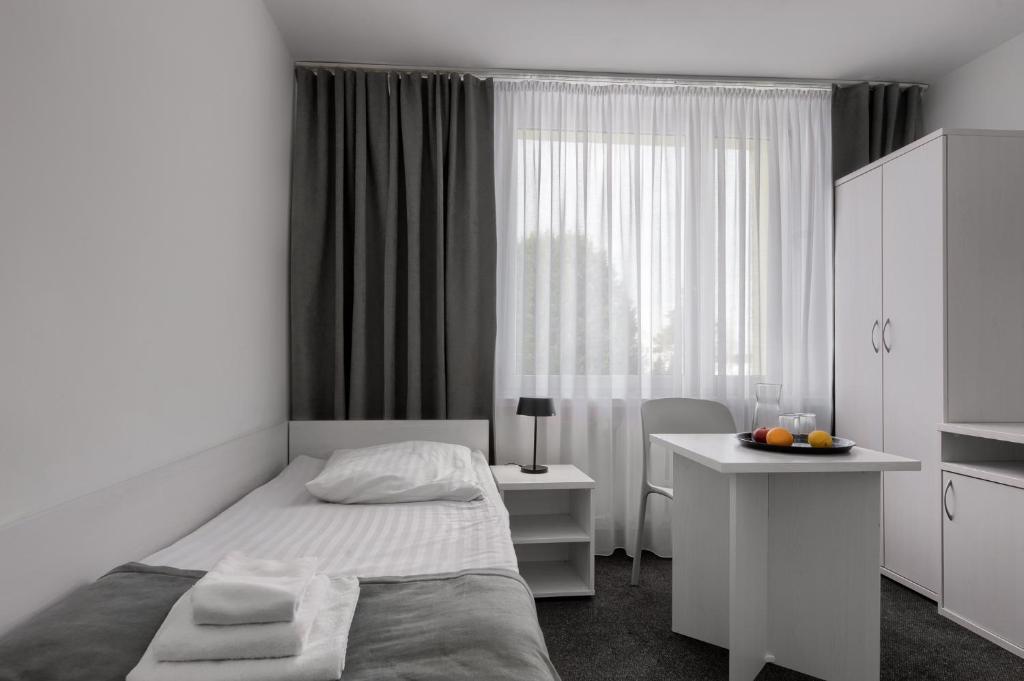 a bedroom with a bed and a desk and a window at Płonia Economy in Szczecin