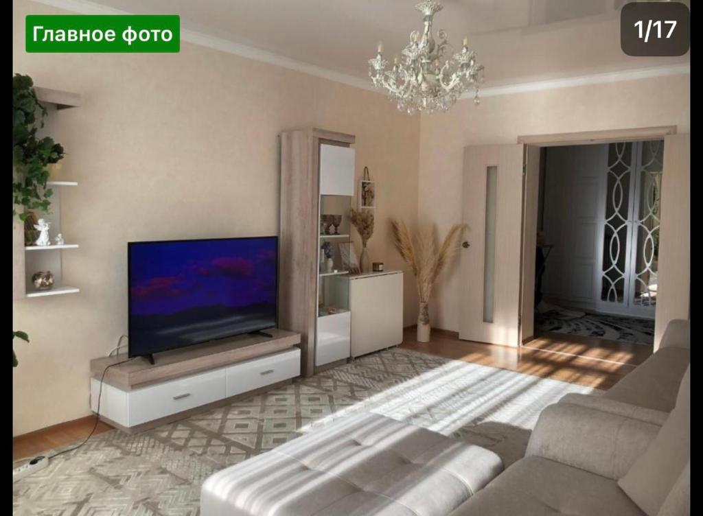 een woonkamer met een bank en een flatscreen-tv bij One room-apart in Prigorodnyy