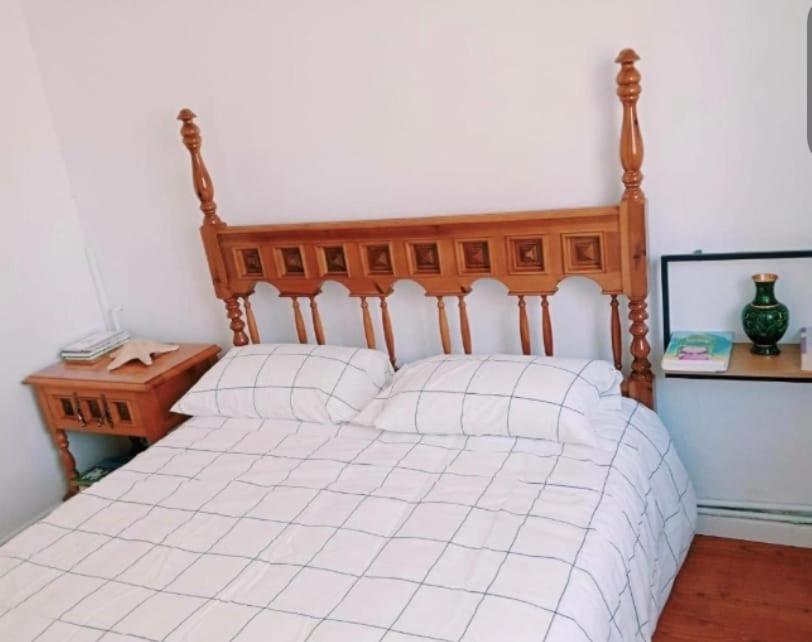 a bedroom with a white bed with a wooden headboard at Habitación pensión Tolima - baño compartido in Cabezón de la Sal