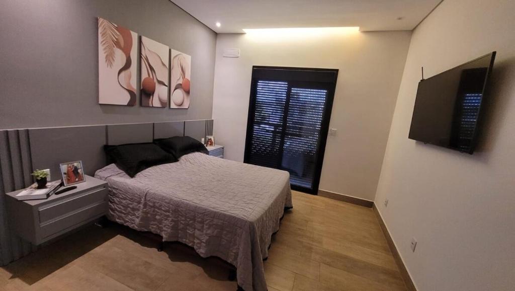 une chambre avec un lit et une télévision à écran plat dans l'établissement Casa de 3 quartos em Franca - Piscina aquecida, banheira, conforto e lazer, à Franca