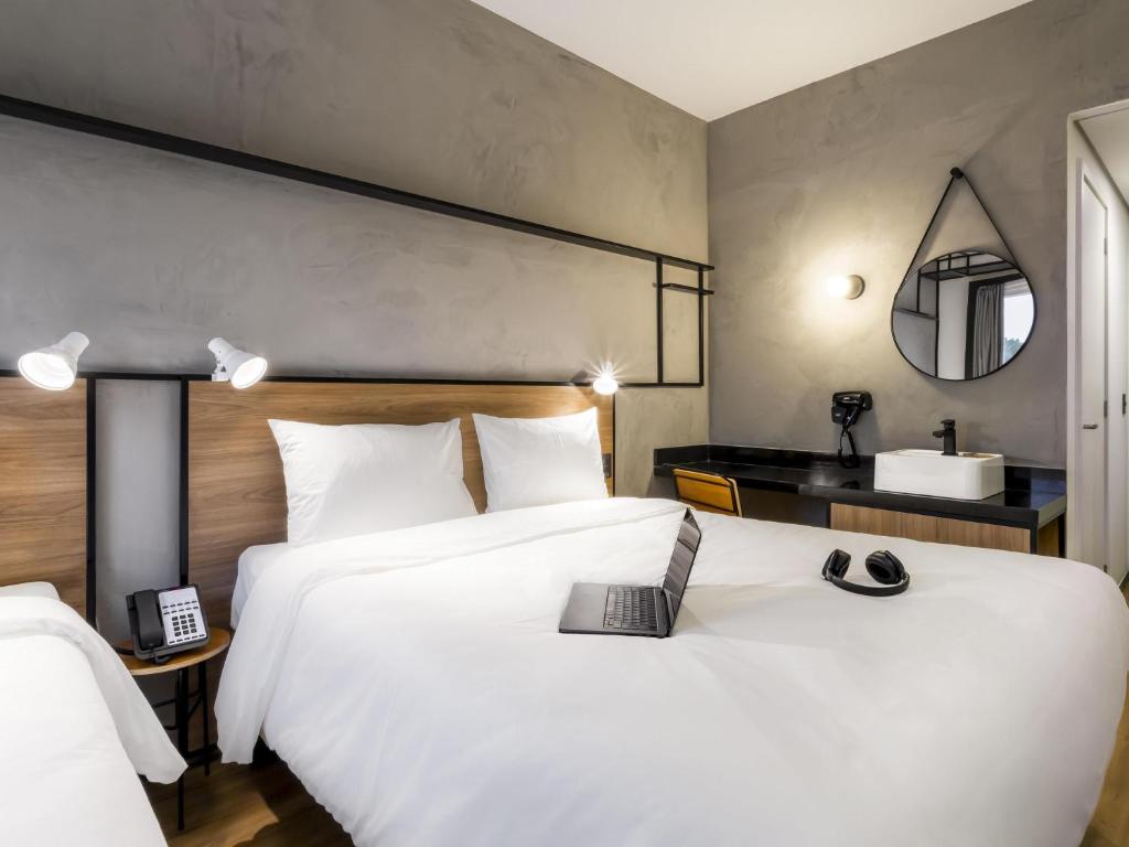 a hotel room with two beds and a mirror at Ibis Aruja in Arujá