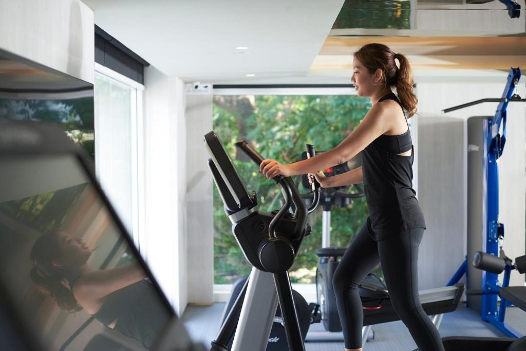 A bright gym scene centered on a cardio machine beside large windows.