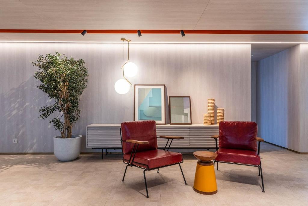 A styled seating nook pairs two red lounge chairs with a small table beside a long console.