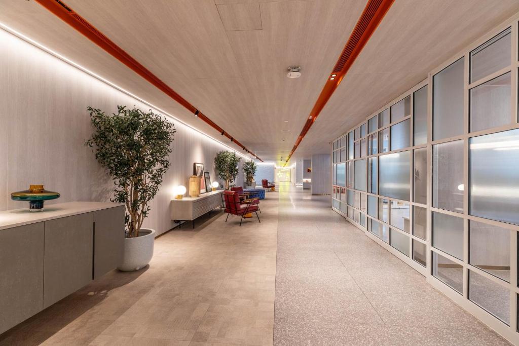 A long lobby passage provides repeated seating and console surfaces beside a frosted glass partition.
