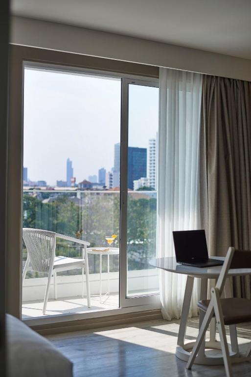 A small laptop workstation beside balcony glazing, with a city view beyond.