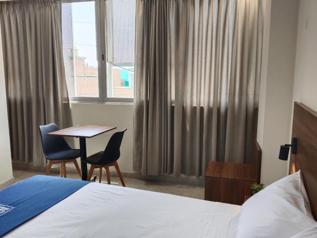 een hotelkamer met een bed, een tafel en stoelen bij Luxotel Business Chincha in Chincha Alta