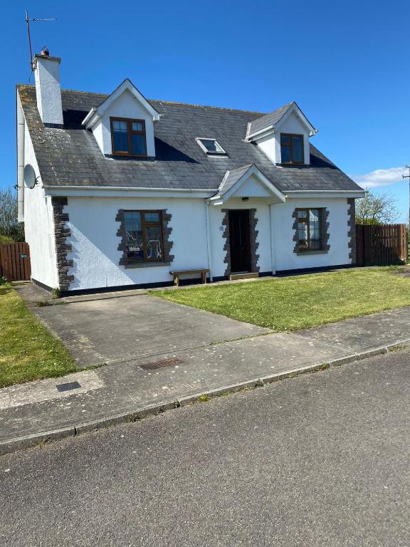 a white house on the side of a street at A spacious 4-Bed home beside the beach in Fethard on Sea