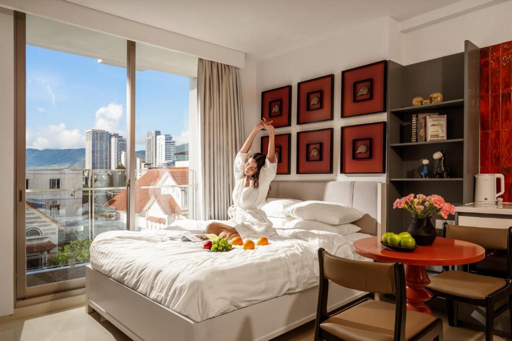 a woman is jumping on a bed in a bedroom at Amber Bay Hotel & Suites Da Nang in Da Nang
