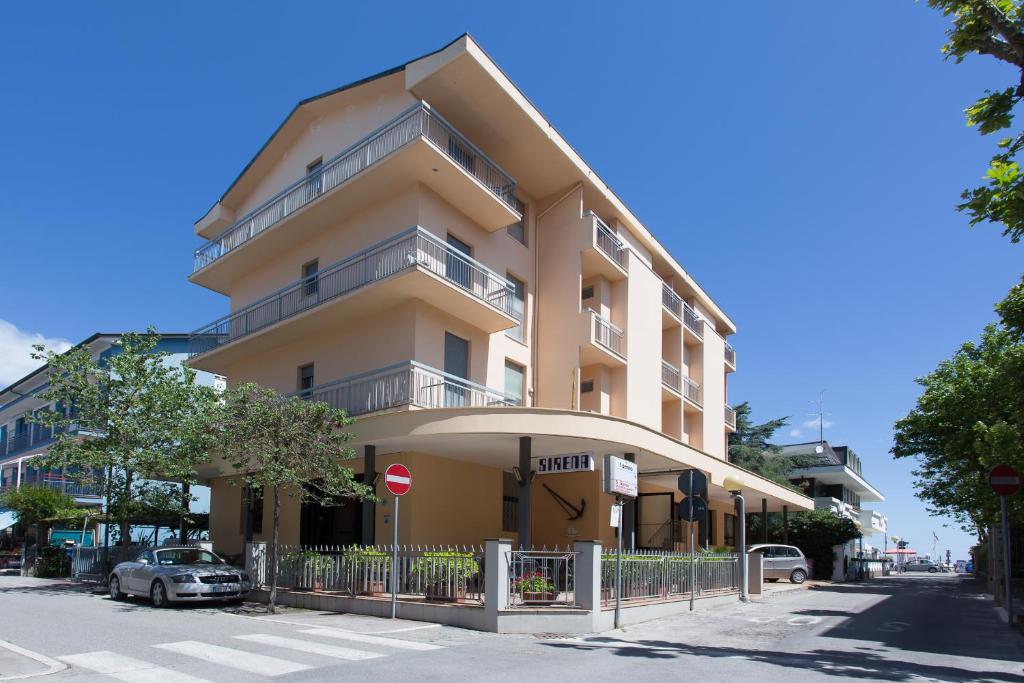 un edificio alto de color amarillo con balcón en una calle en Hotel Sirena, en Bellaria-Igea Marina