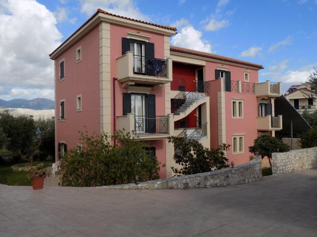 ein rosafarbenes Gebäude mit Balkon an der Seite in der Unterkunft Kolona Apartments in Lixouri