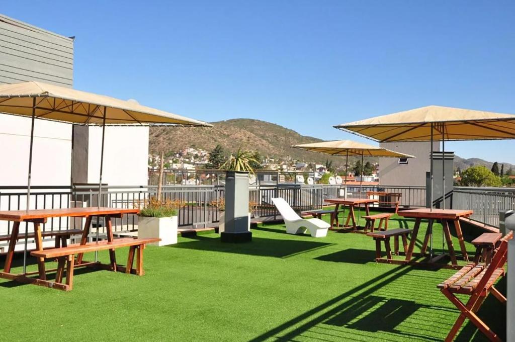 eine Terrasse mit Tischen und Sonnenschirmen auf dem Dach in der Unterkunft DPto Carlos Paz in Villa Carlos Paz