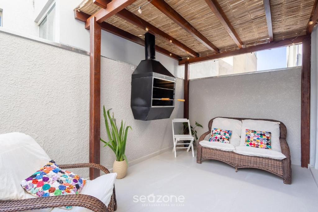 a patio with two wicker chairs and a stove at Apto c/ Churrasqueira a 230 m da Praia SHA0104 in Piçarras