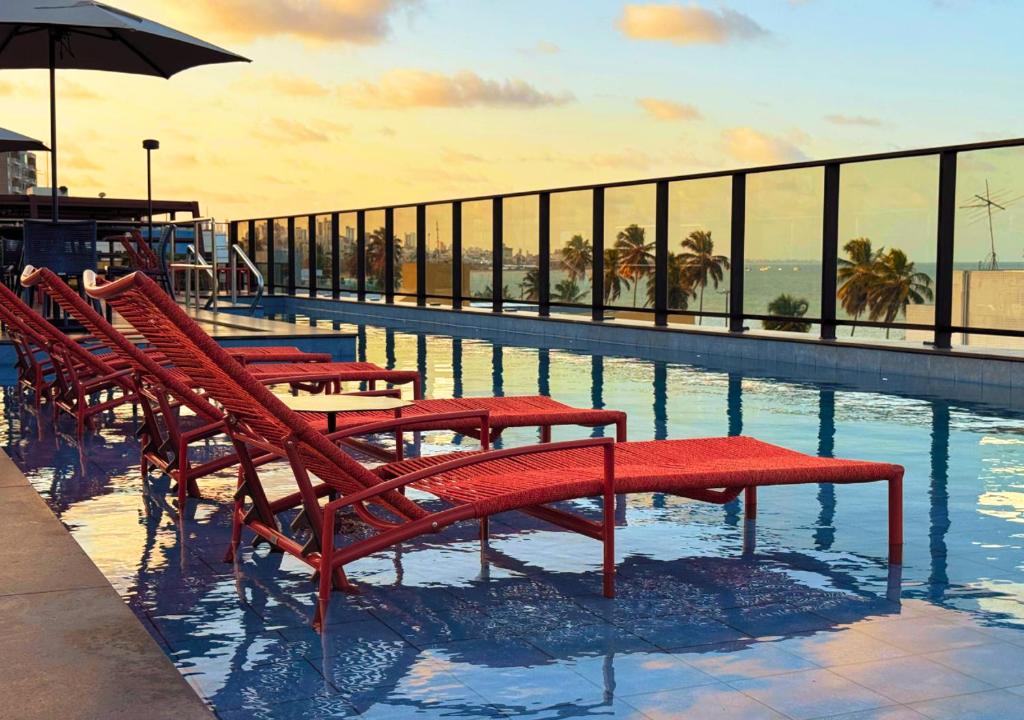 a row of red benches sitting in a swimming pool at Nord Class Rio 83 in João Pessoa