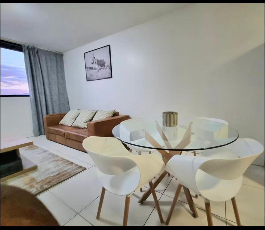 a dining room with a glass table and white chairs at ProAvia Apartments and Hotel in Windhoek