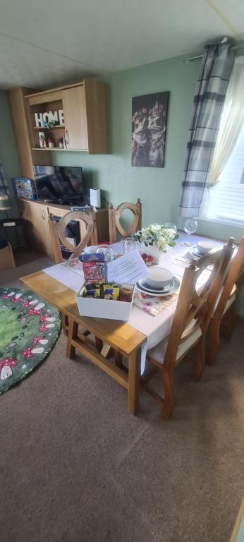 einem Esstisch mit Stühlen und einem Tisch mit Essen darauf in der Unterkunft Lyons Winkups Holiday Park Towyn, North Wales static Caravan 3 bedroom sleeps 8 free entertainment in Kinmel Bay