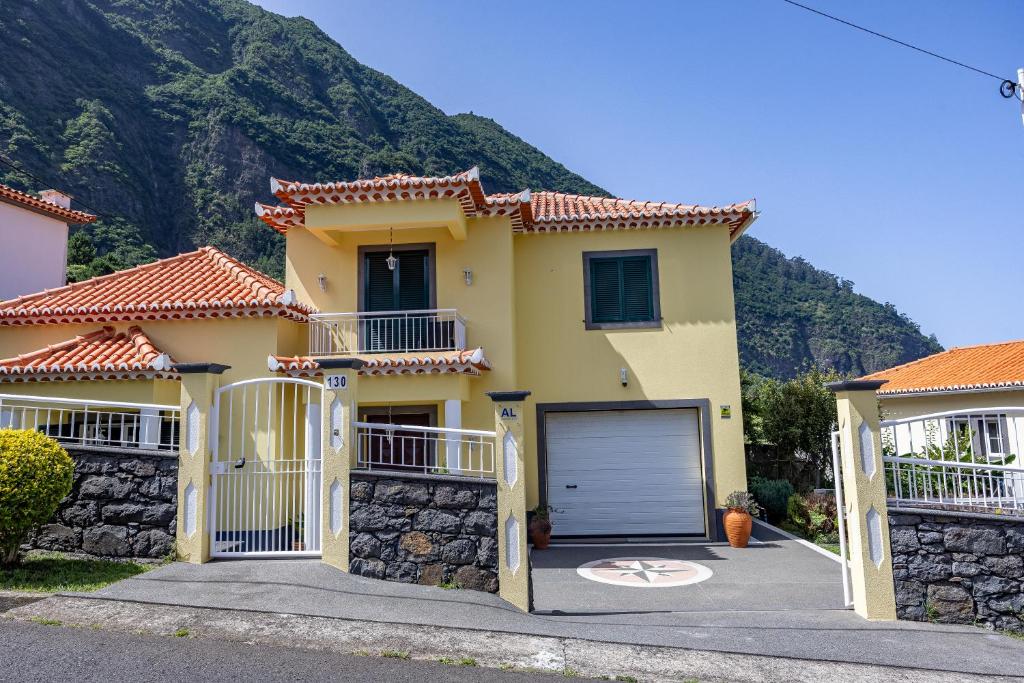 ein gelbes Haus mit einer Garage vor einem Berg in der Unterkunft Casa Golino by YOUR KEY in São Vicente
