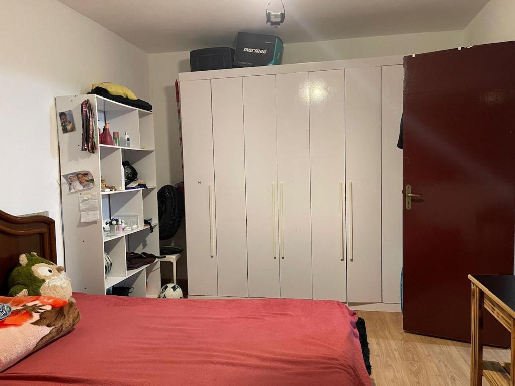 een slaapkamer met witte kasten en een rood bed bij Casa Kekel in Florianópolis