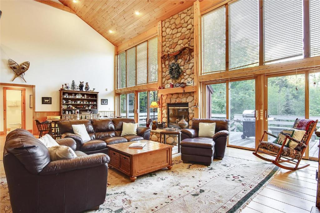 a living room with leather furniture and a stone fireplace at Redwood in Stowe Fork