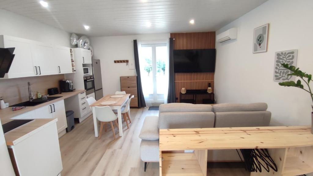 a kitchen and living room with a couch and a table at Studio lumineux avec terrasse au cœur du Périgord in Monestier