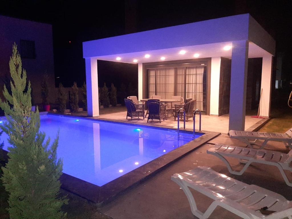 a swimming pool at night with a table and chairs at Oa Ceșme Villa in Cesme