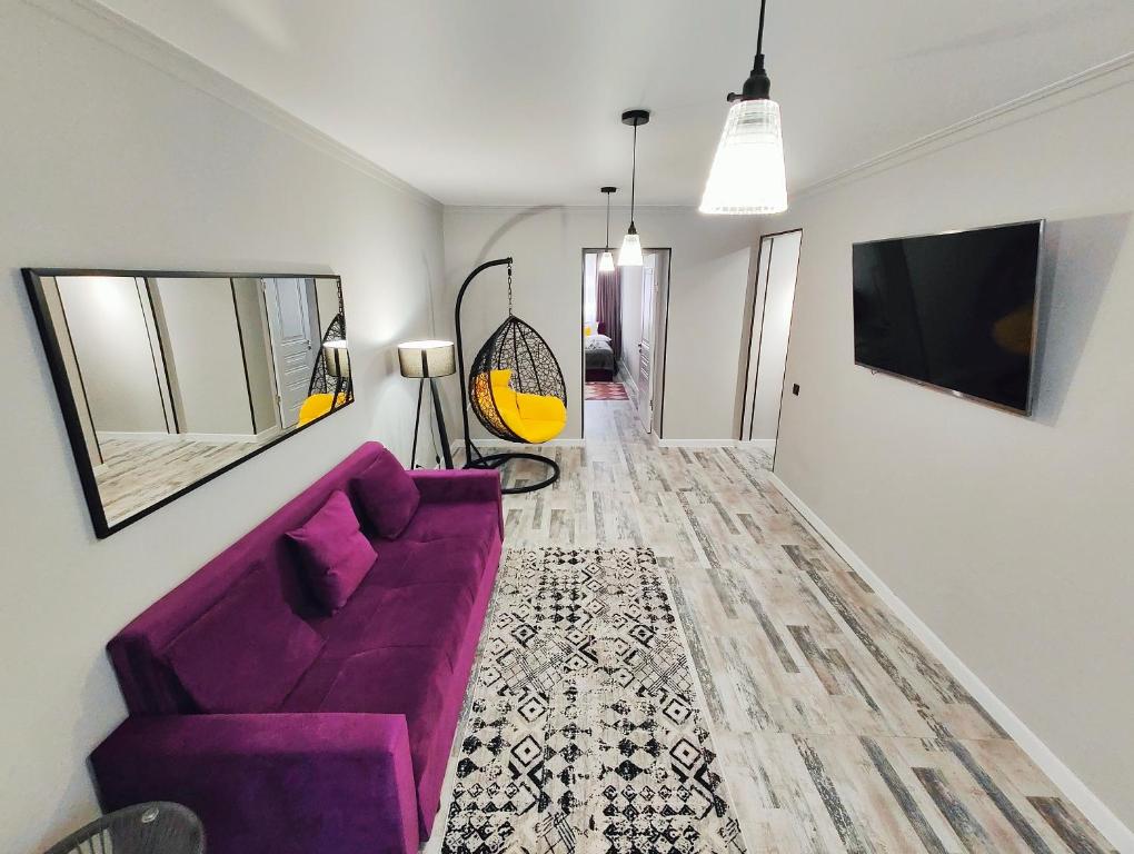 un salon avec un canapé violet et un couloir dans l'établissement Арбат в Золотом квадрате двухкомнатная стильная в центре 25, à Almaty