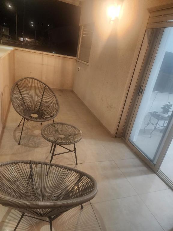two chairs and tables in a room with a window at חדרי אירוח ליאורה in Qiryat Shemona
