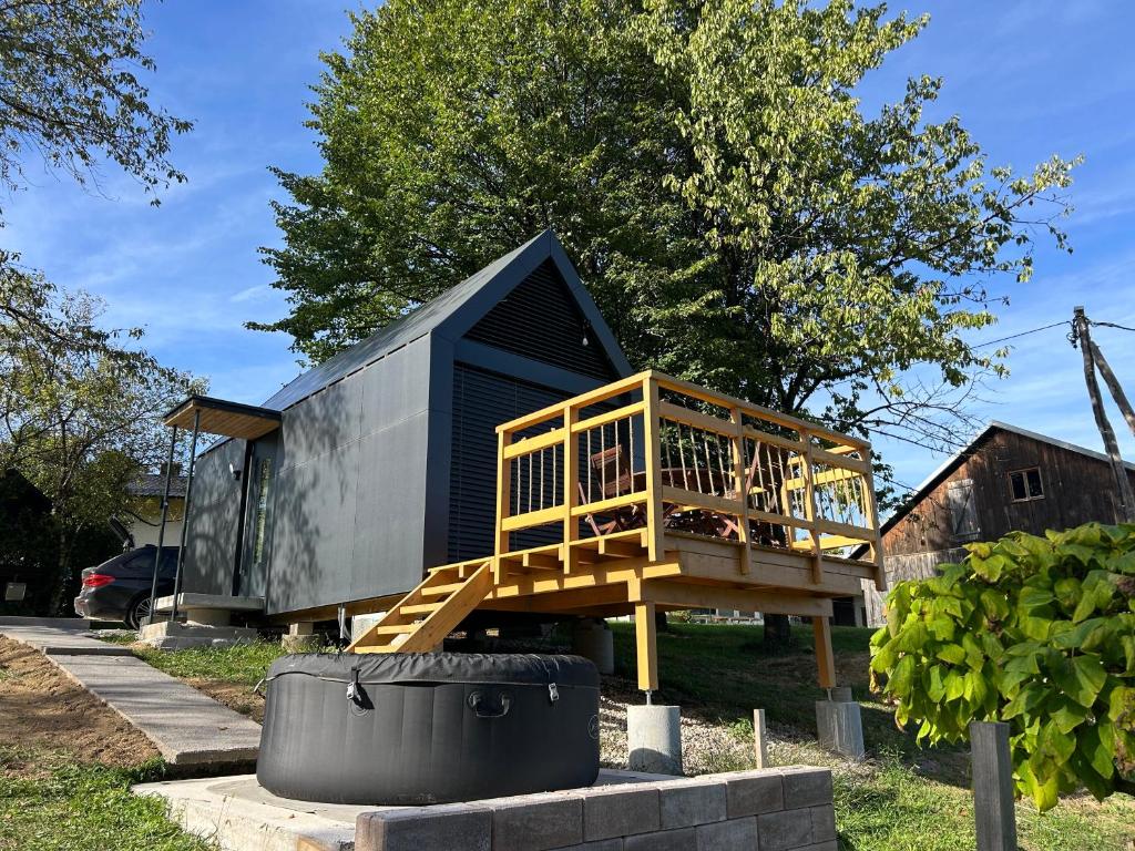 a small black house with a wooden deck at La - Mai Glamping in Žetale