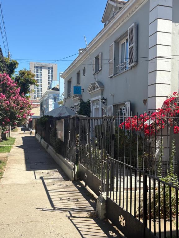 a fence in front of a white house with pink flowers at Hostal Casa Gloria Home in Viña del Mar