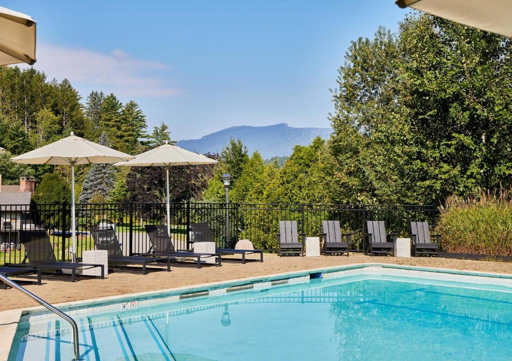 a swimming pool with lounge chairs and umbrellas at Bluebird Cady Hill Lodge in Stowe