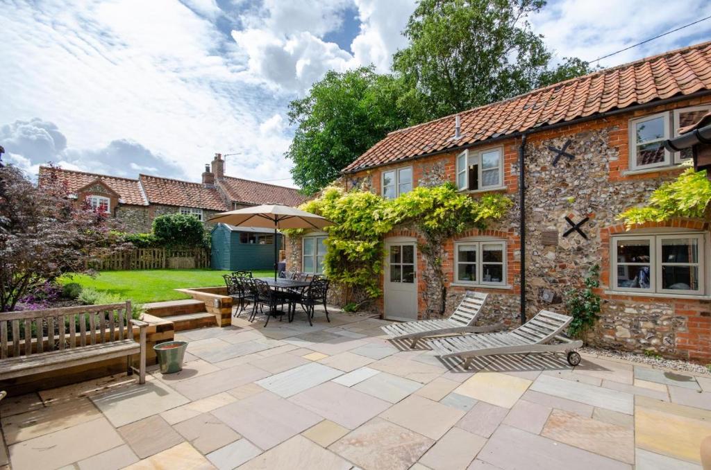 a stone house with a patio with a table and chairs at Willow Cottage in Wighton