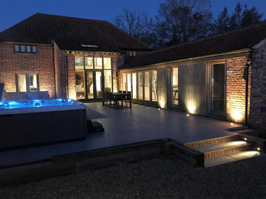 a large patio with a hot tub in front of a building at The Granary in Banningham
