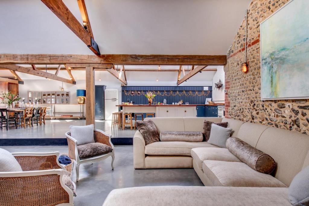 Una sala de estar con un sofá y sillas y una cocina. en The Cattle Shed, en Wighton