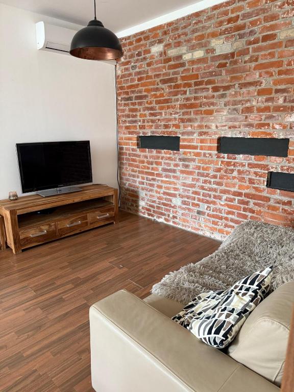 a living room with a brick wall and a couch at CosyCentrumFlat in Slezská Ostrava
