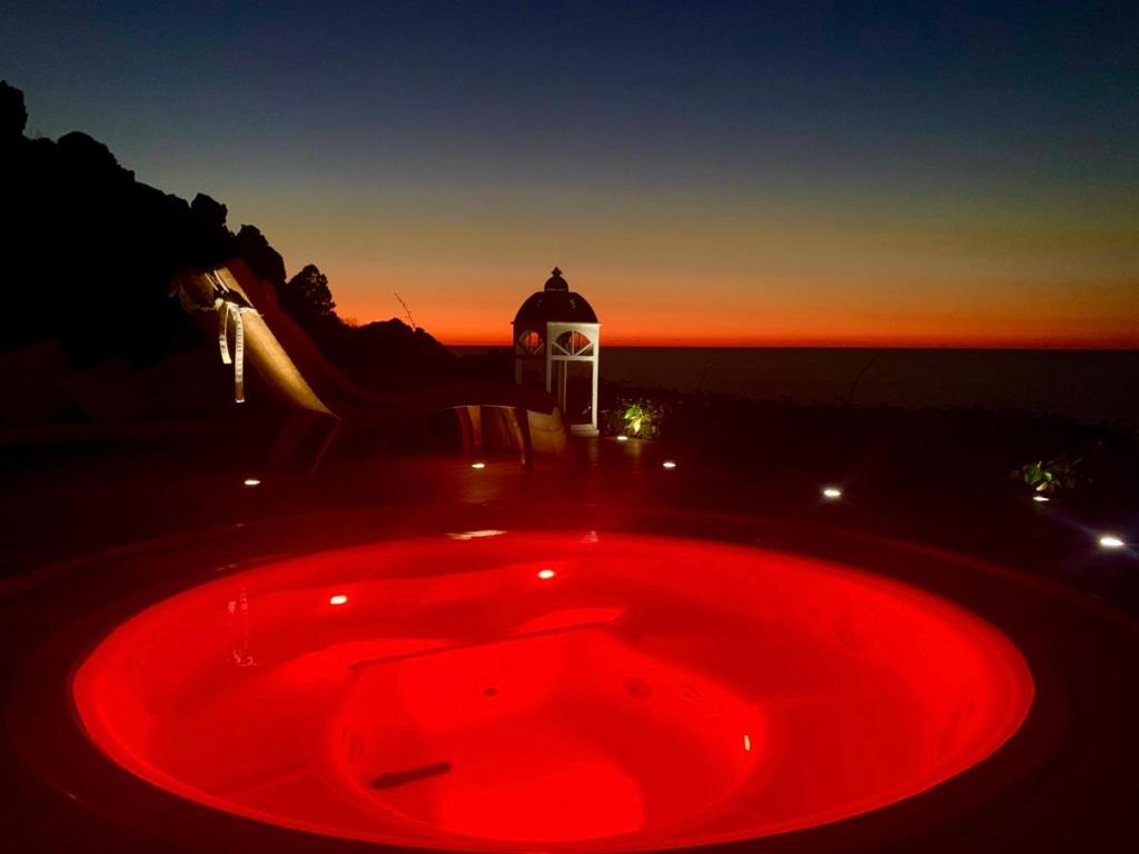 a red bath tub with a sunset in the background at Villa La Dolce Vista & Jacuzzi in Costa Paradiso