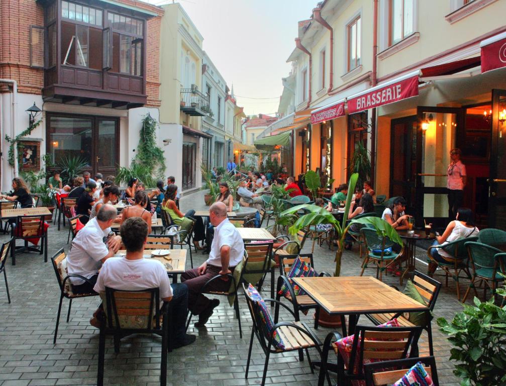 un grupo de personas sentadas en las mesas fuera de un restaurante en Homestay Nika en Tiflis