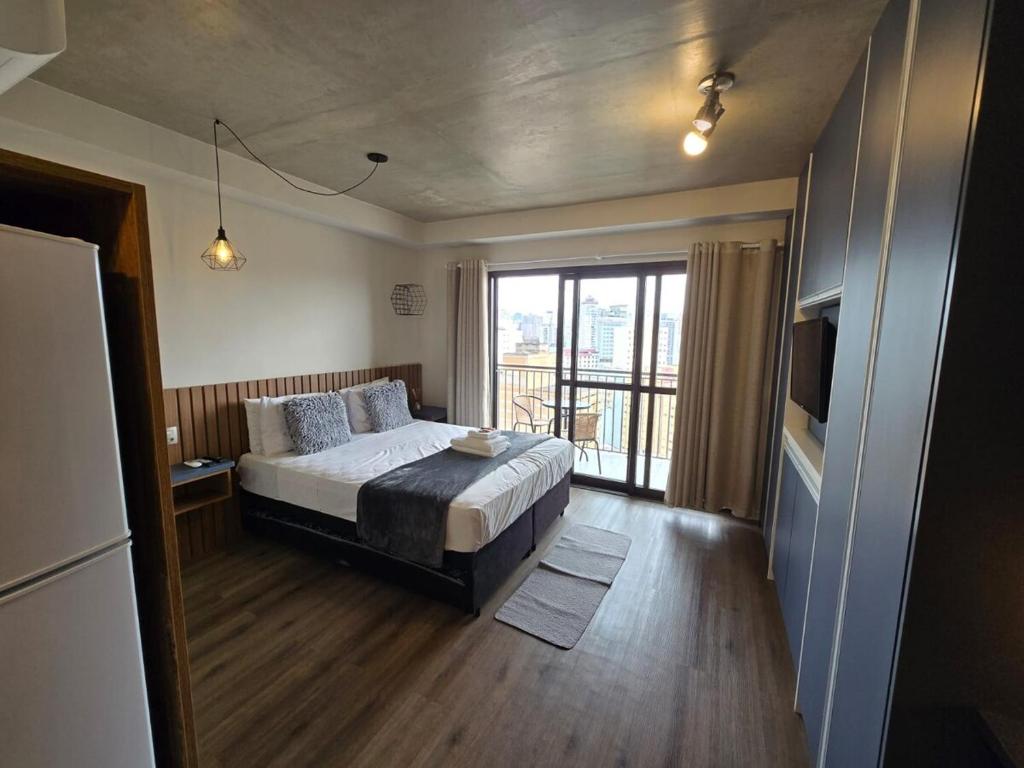 a bedroom with a bed and a large window at Conforto no Largo do Arouche 77 c Varanda, Lazer e Vista A 250m do Metrô in São Paulo