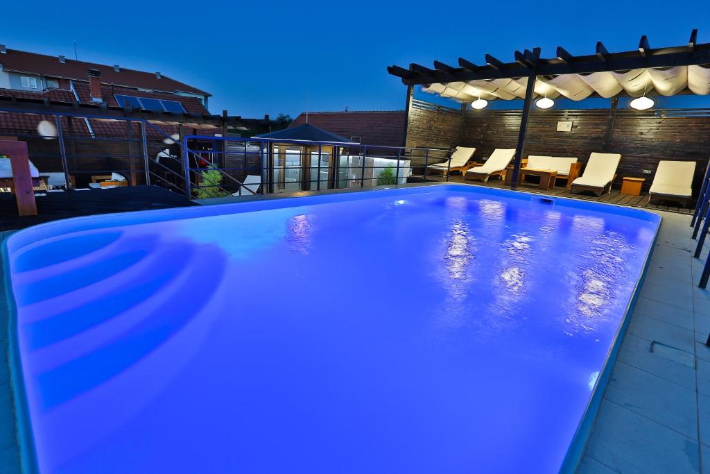 a blue swimming pool in a backyard at night at Garni Hotel Zen in Niš